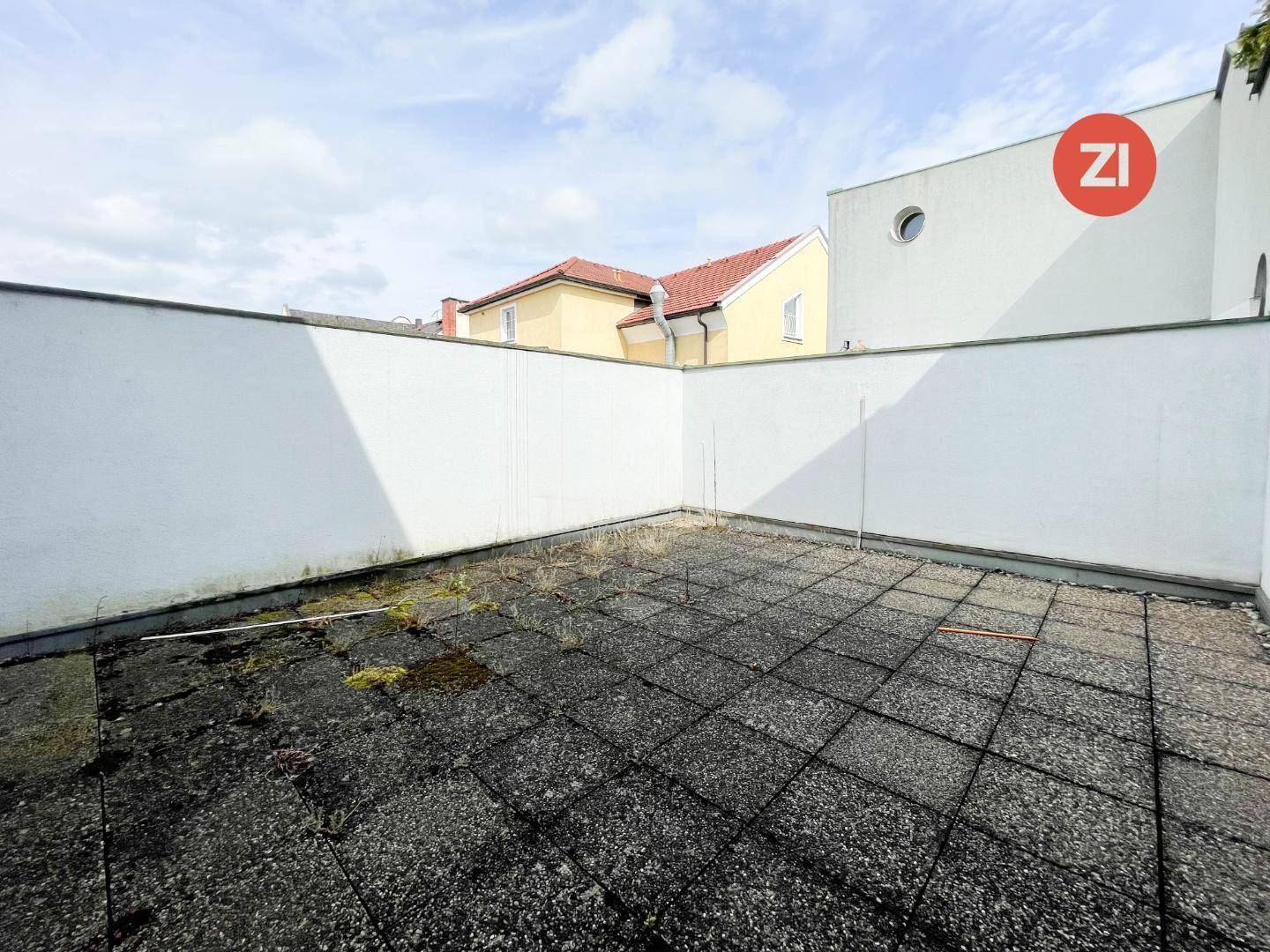 Unmöblierte Dachterrasse mit Fliesenboden und hohen Mauern, die Privatsphäre bieten.