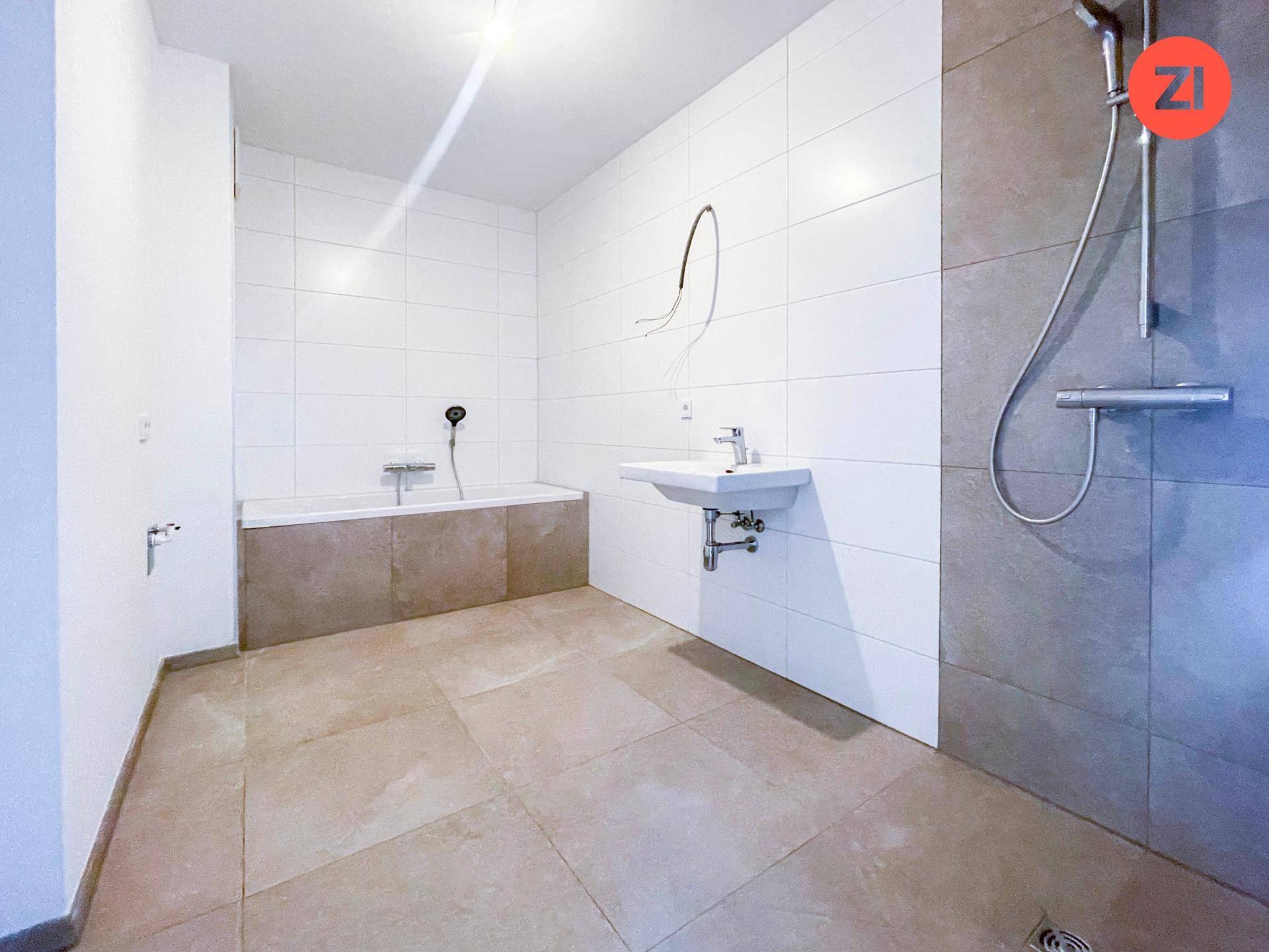 Modernes Badezimmer mit Badewanne, Dusche und Wandwaschbecken in hellen Fliesen.