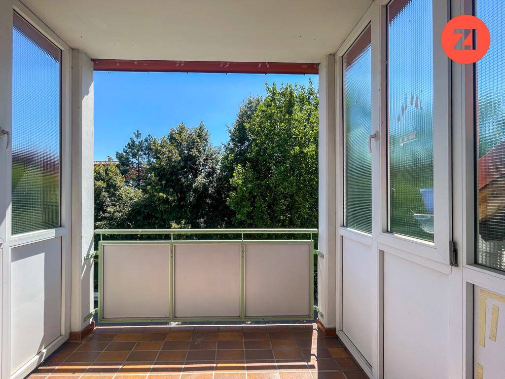 Heller Balkon mit Fliesenboden und Blick ins Grüne, ideal zum Entspannen im Freien.