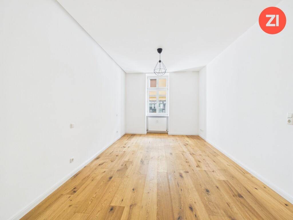 Helles Zimmer mit Holzboden und einem Fenster, ideal als Wohn- oder Arbeitsbereich.