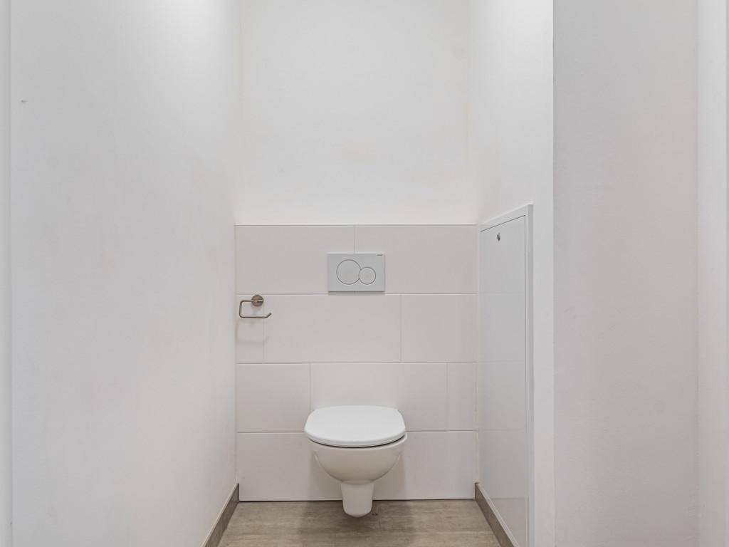 Modernes Gäste-WC mit wandhängender Toilette und weißen Fliesen.