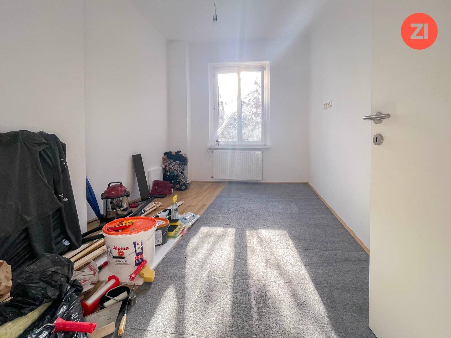 Zimmer in Renovierung mit Teppich- und Holzboden, bereit für die Fertigstellung.