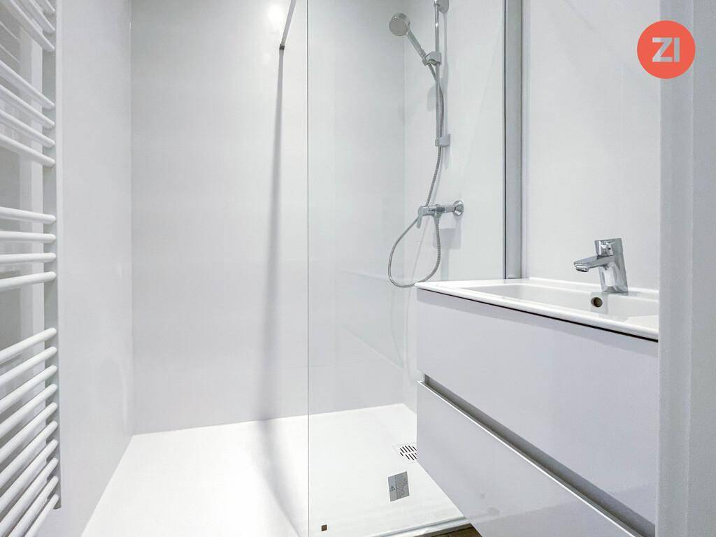 Modernes Badezimmer mit ebenerdiger Dusche, Glasabtrennung und weißem Waschtisch.
