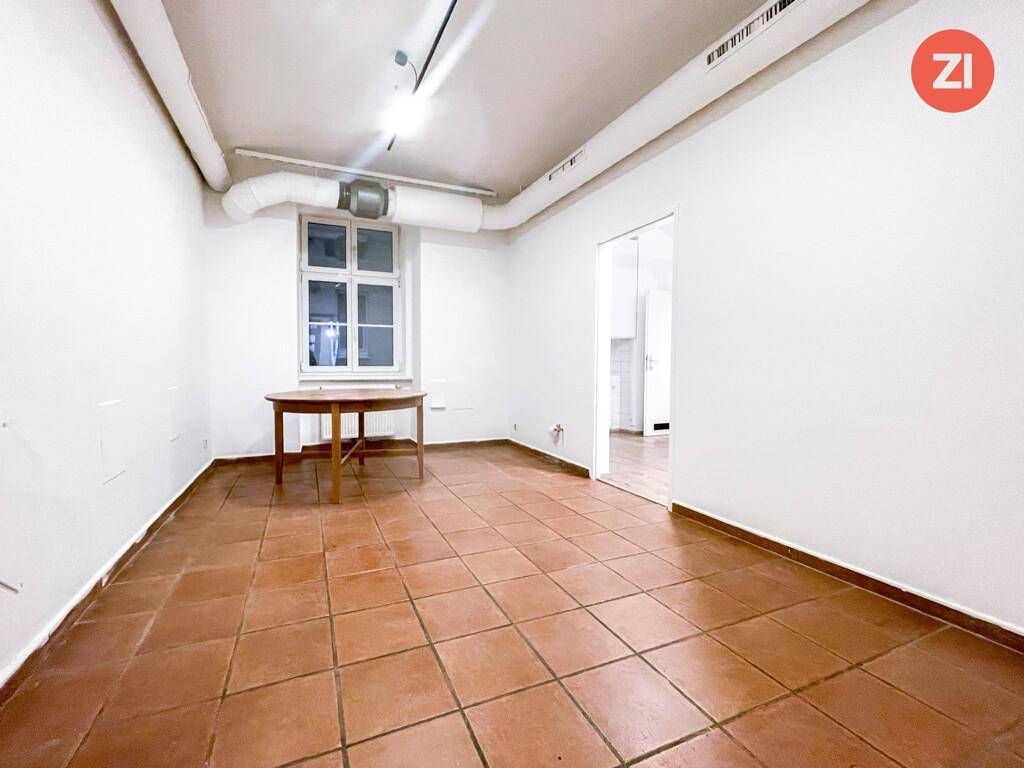 Raum mit Terrakottafliesenboden, weißen Wänden, einem Fenster und einem runden Holztisch.