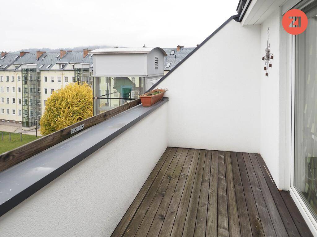 Kleiner Balkon mit Holzboden und Blick auf die umliegenden Gebäude.
