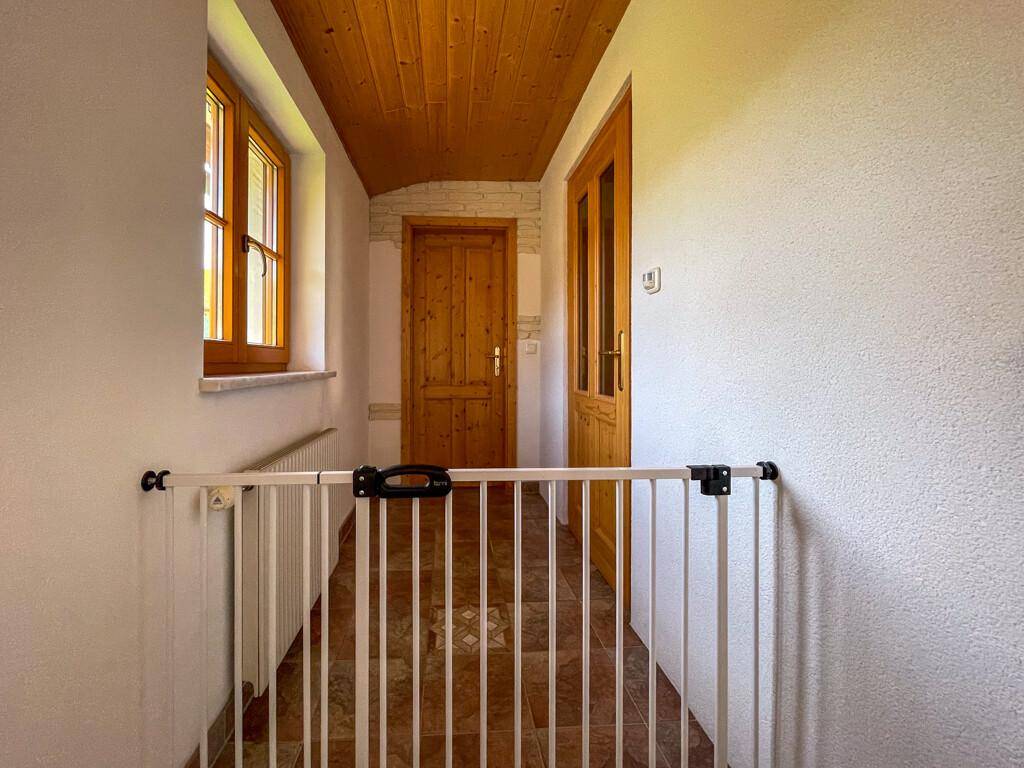 Heller Flur mit Holzdecke, Fliesenboden und einem praktischen Kinderschutzgitter.