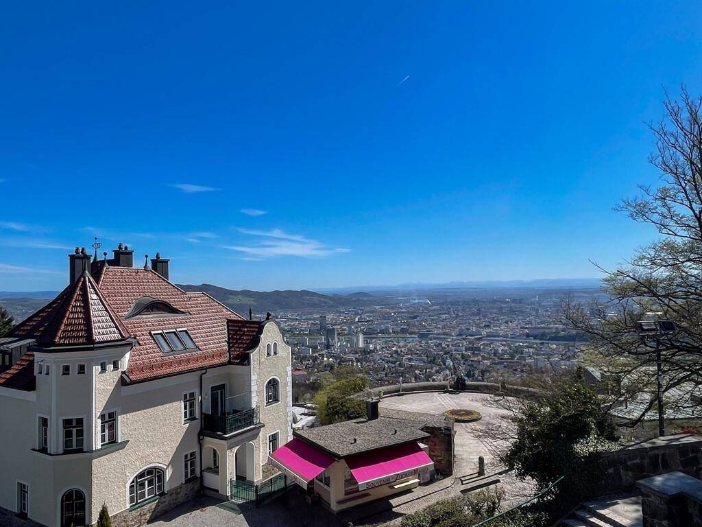 Gebäude mit einzigartigem Dach und großer gepflasterter Fläche, mit Panoramablick über die Stadt.