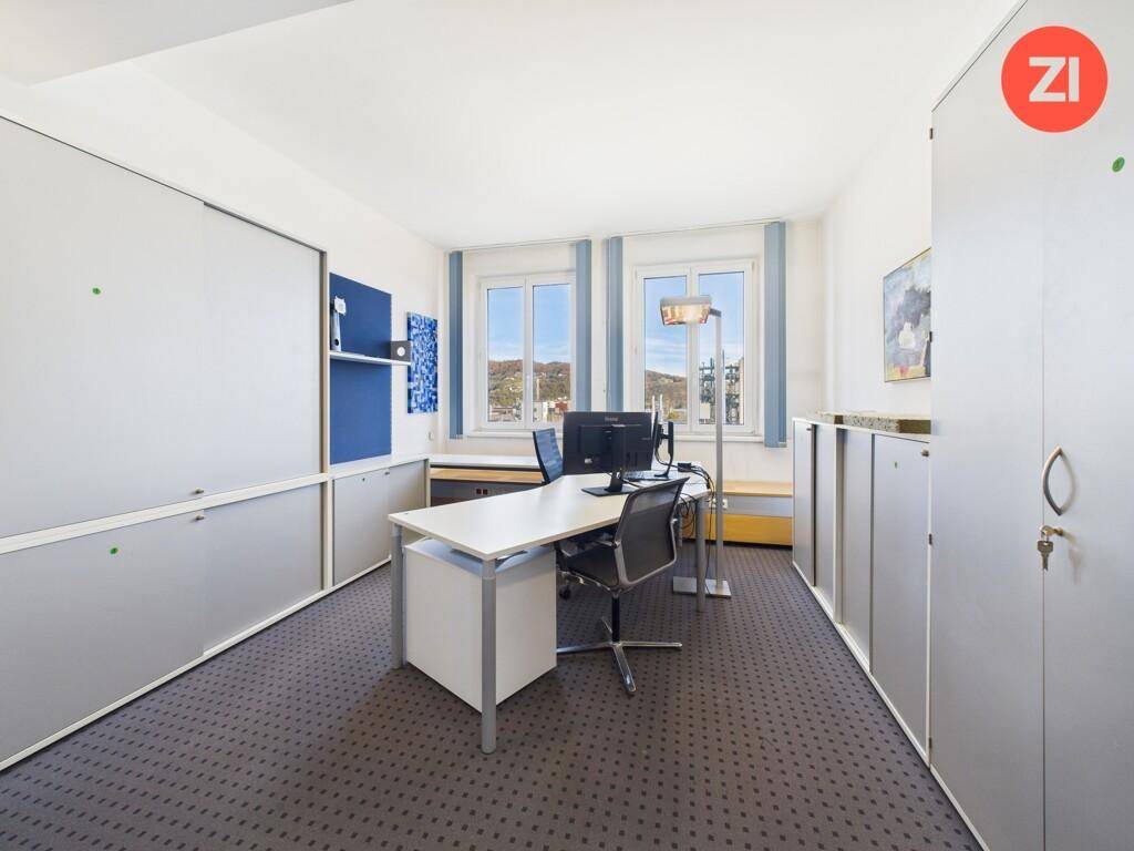 Helles Einzelbüro mit Schreibtisch, Bürostuhl und integrierten Schränken entlang der Wand.