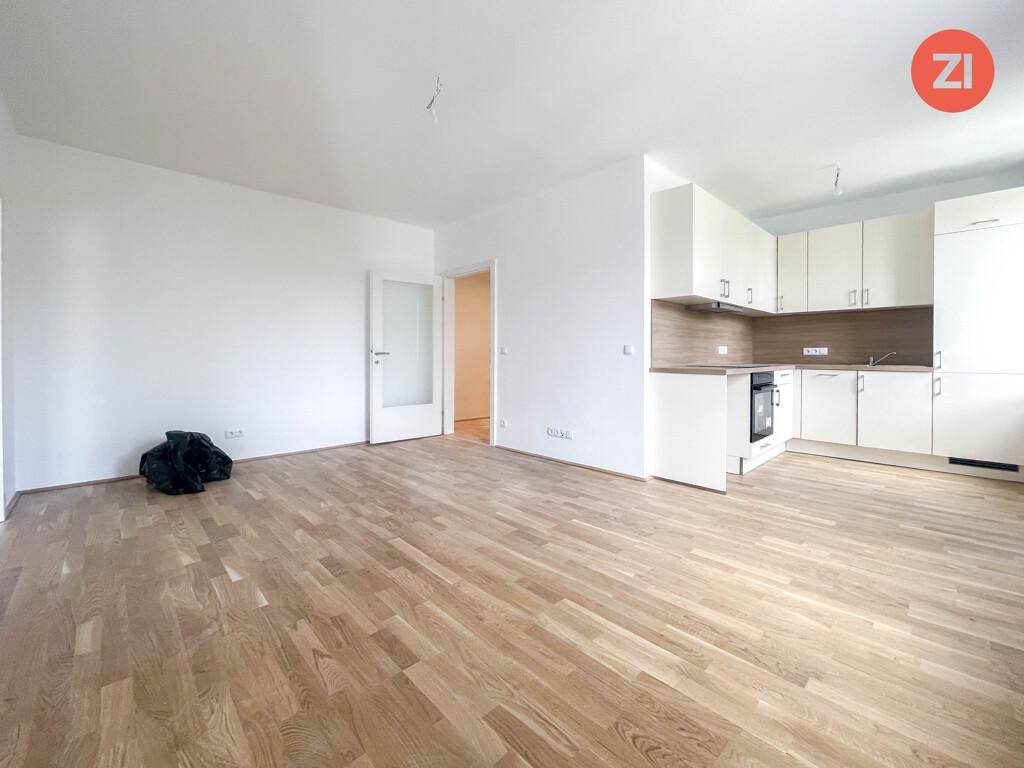 Offener Wohn- und Essbereich mit integrierter Küche und hellem Holzparkettboden, ideal für modernes Wohnen.