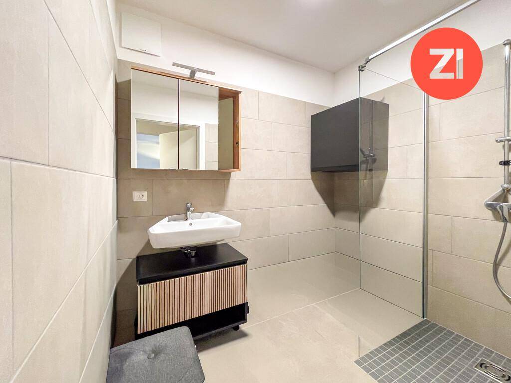 Modernes Badezimmer mit ebenerdiger Dusche, Waschbecken und Spiegelschrank.