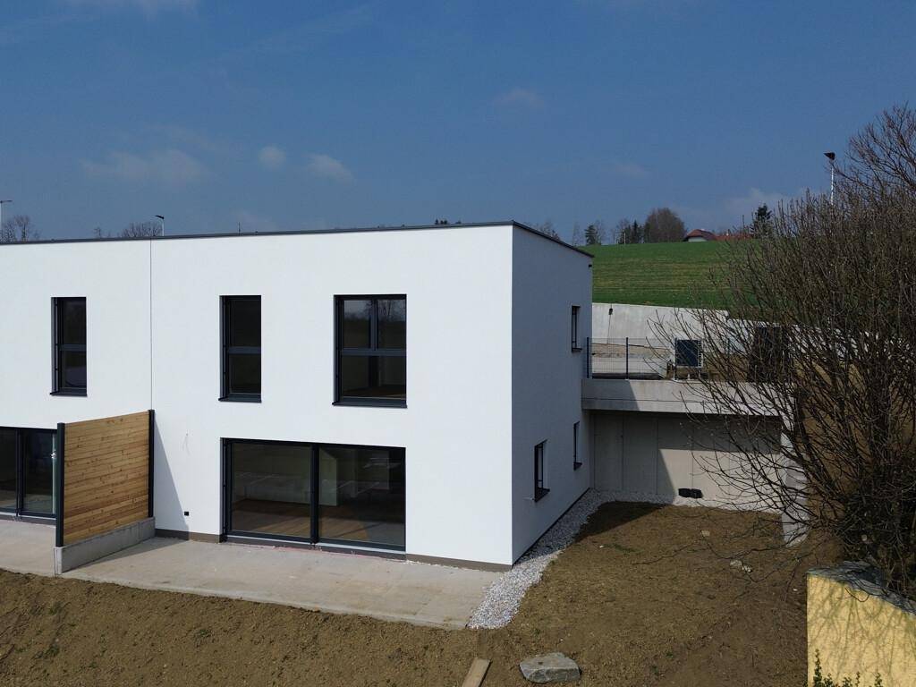 Moderne Architektur des Neubaus mit Flachdach und angrenzendem Gartenbereich.