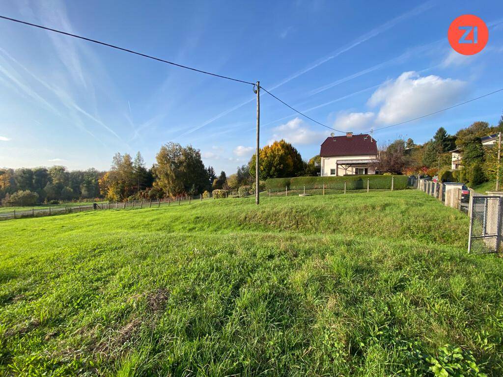 Weitläufiges grünes Grundstück mit einem Haus und Hecken im Hintergrund unter blauem Himmel.