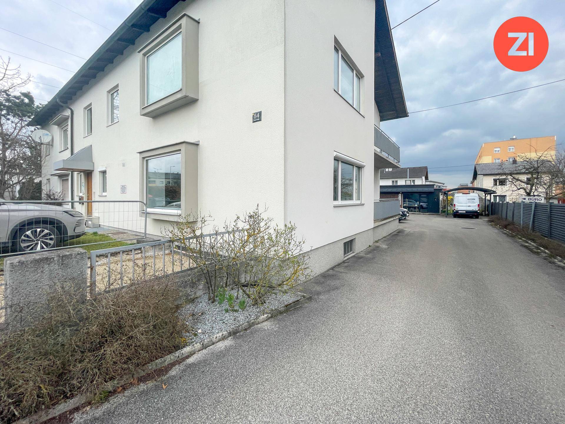 Seitenansicht eines modernen Gebäudes mit gepflegter Außenanlage und Zufahrt.