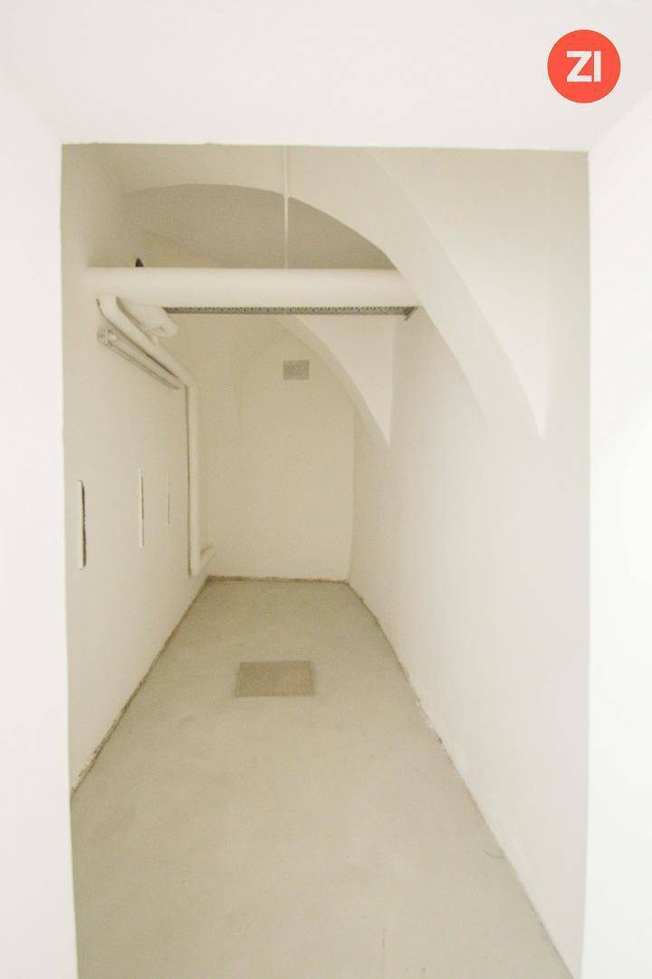 Schmaler Flur mit gewölbter Decke und sichtbaren Leitungen an der Wand, funktional und schlicht.