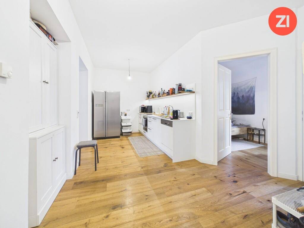 Offene Küche mit Holzboden, weißen Schränken und einem großen Kühlschrank.