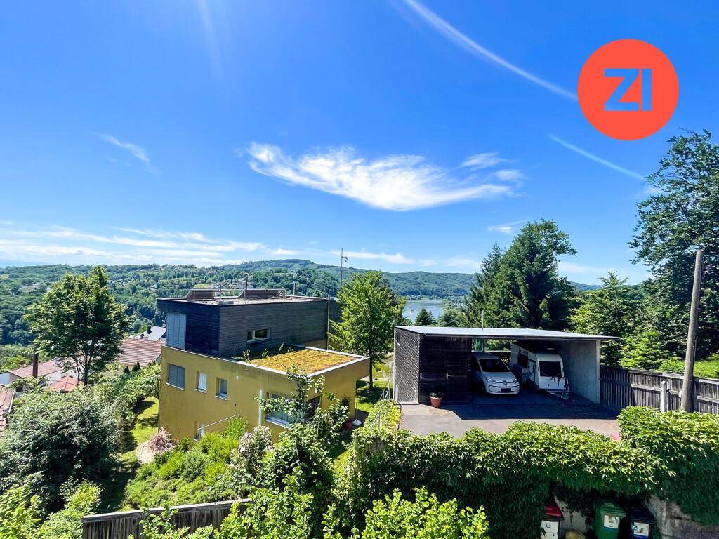 Ausblick auf mehrere Häuser, einen Carport und einen See oder großen Fluss in der Ferne.