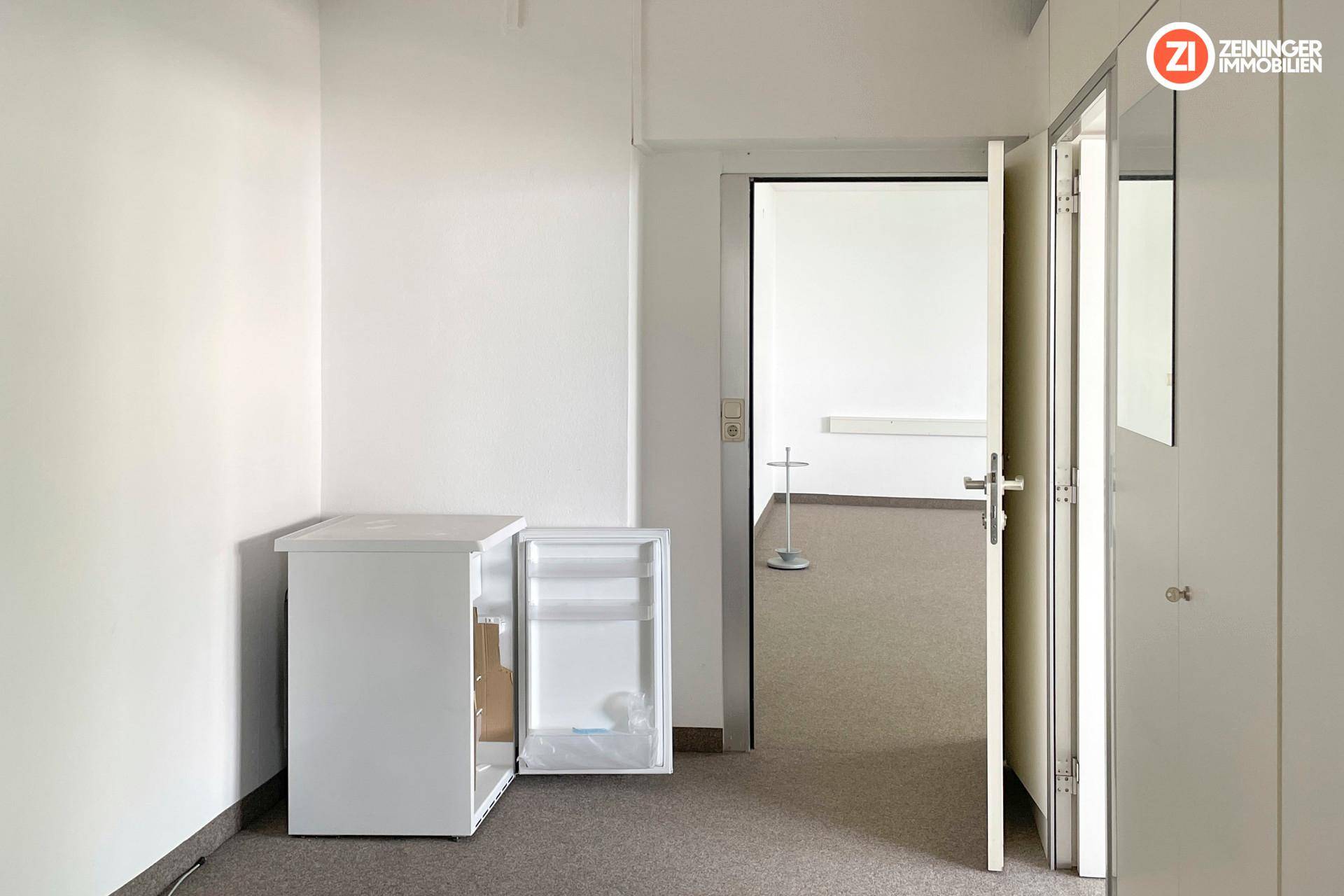 Funktionaler Bereich mit kleinem Kühlschrank und Zugang zu weiteren Büroräumen, ausgestattet mit Einbauschränken.