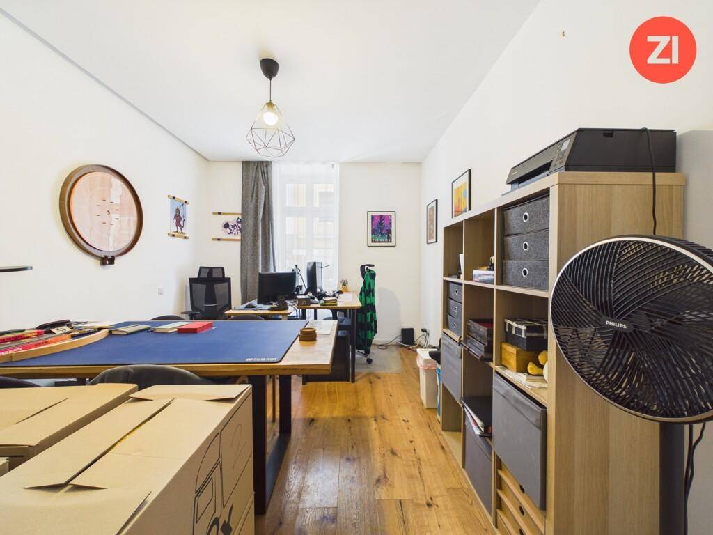 Helles Arbeitszimmer mit Holzboden, Schreibtischen und Regalen für Stauraum.
