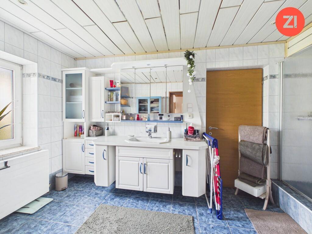 Geräumiges Badezimmer mit Doppelwaschbecken, Badewanne und blauen Fliesen.