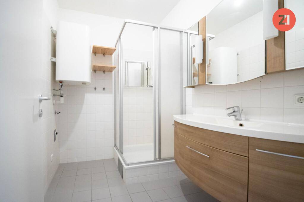 Modernes Badezimmer mit Duschkabine, Waschbeckenunterschrank und hellen Fliesen.