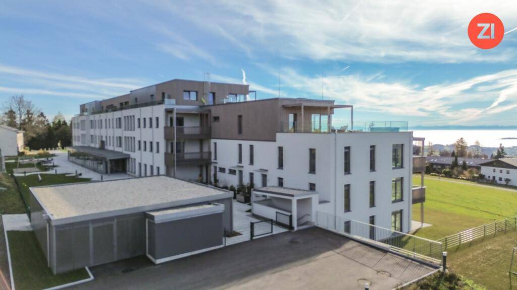 Panoramablick auf einen modernen Neubau mit Balkonen und Terrassen, umgeben von grüner Natur.