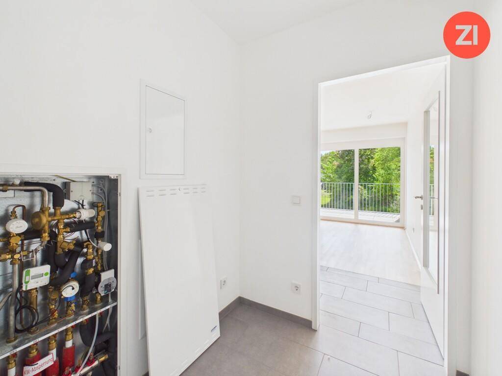 Technikraum mit sichtbarer Heizungsanlage und Fliesenboden, angrenzend an einen hellen Wohnbereich.