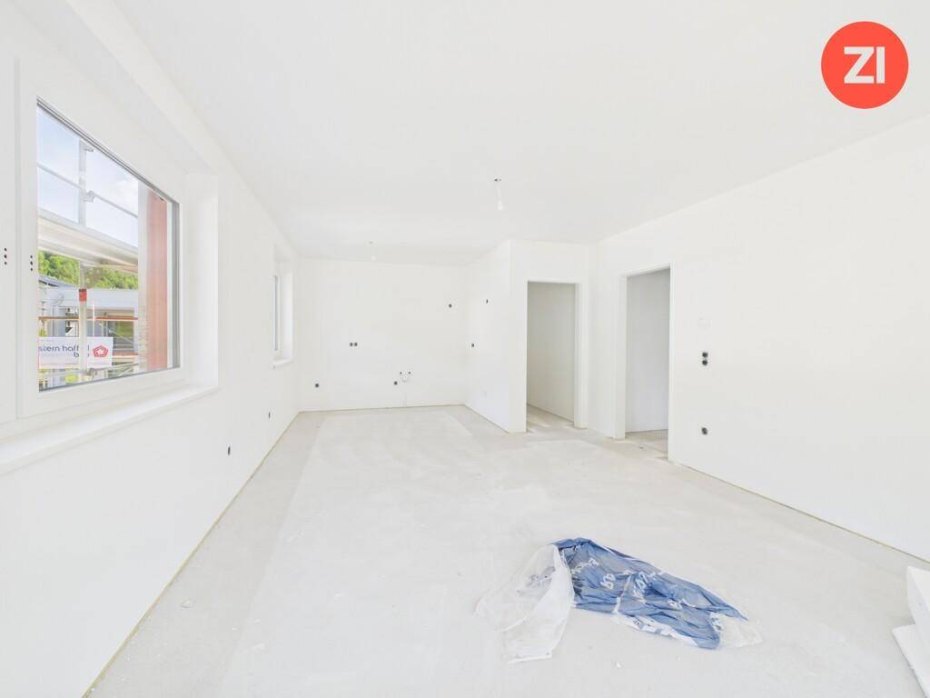 Helles, unfertiges Zimmer mit weißen Wänden und einem großen Fenster.