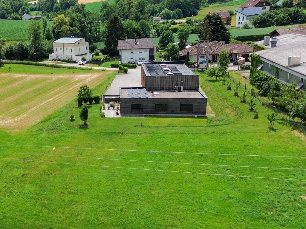 Luftaufnahme des modernen Gebäudekomplexes mit Solaranlagen, Parkplatz und ländlicher Umgebung.