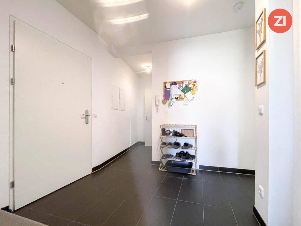 Heller Eingangsbereich mit dunklen Fliesen und Garderobe.