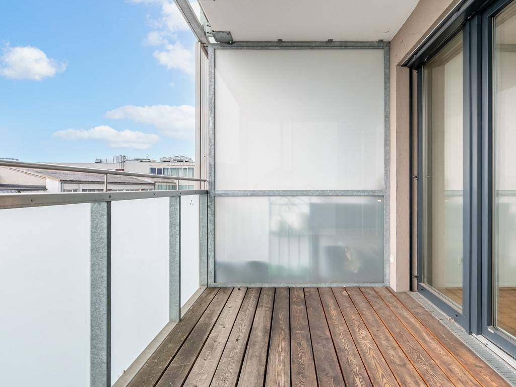 Geräumiger Balkon mit Holzboden und Milchglasbrüstung, ideal zum Entspannen.