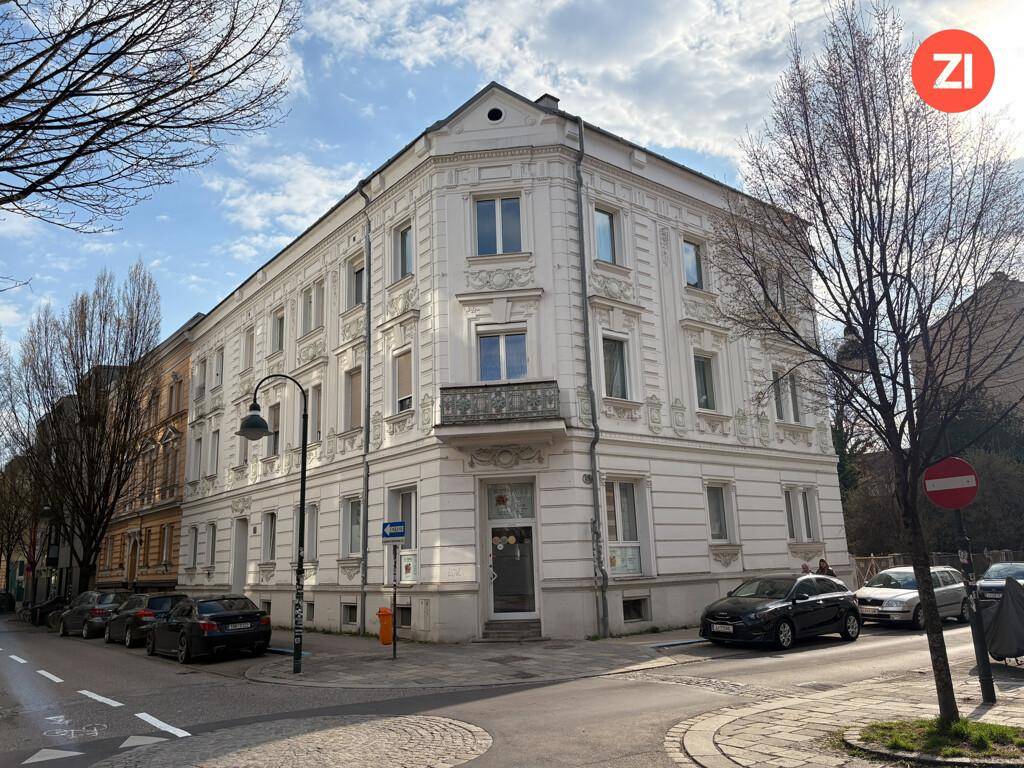 Klassisches Wohnhaus an einer Straßenecke mit weißer Fassade und vielen Fenstern.