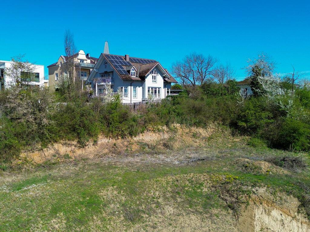 Charmantes Haus auf einem Hügel mit Photovoltaik auf dem Dach, umgeben von üppigem Grün.