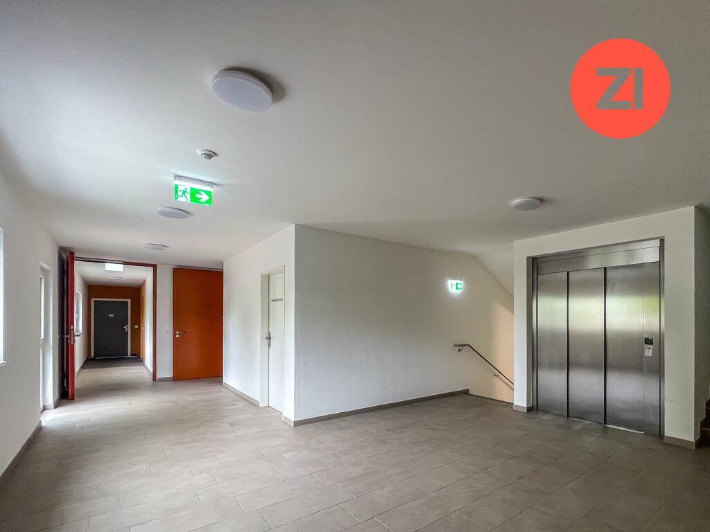 Geräumiger Flur im Gebäude mit Aufzug, Fliesenboden und Zugang zu weiteren Wohnungen.
