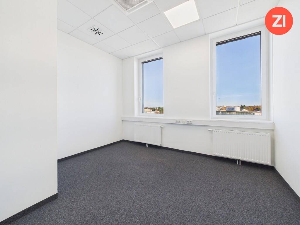 Kleineres Büro mit Teppichboden, weißen Wänden und zwei großen Fenstern.