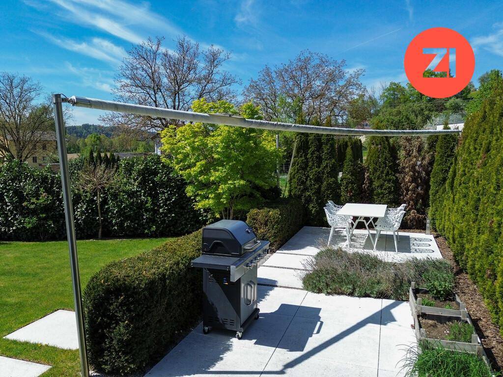 Gemütlicher Grillbereich im Garten mit Esstisch und Stühlen, ideal für Sommerabende.