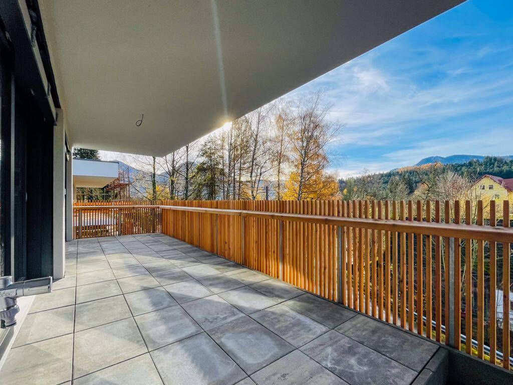 Breiter Balkon mit Fliesenboden und Holzgeländer, bietet einen malerischen Blick auf die Berge.