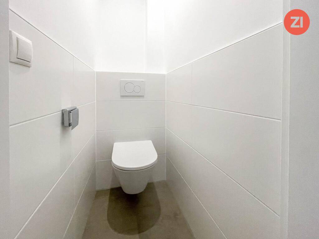 Sauberer, separater WC-Raum mit wandhängender Toilette und weißen Fliesen.
