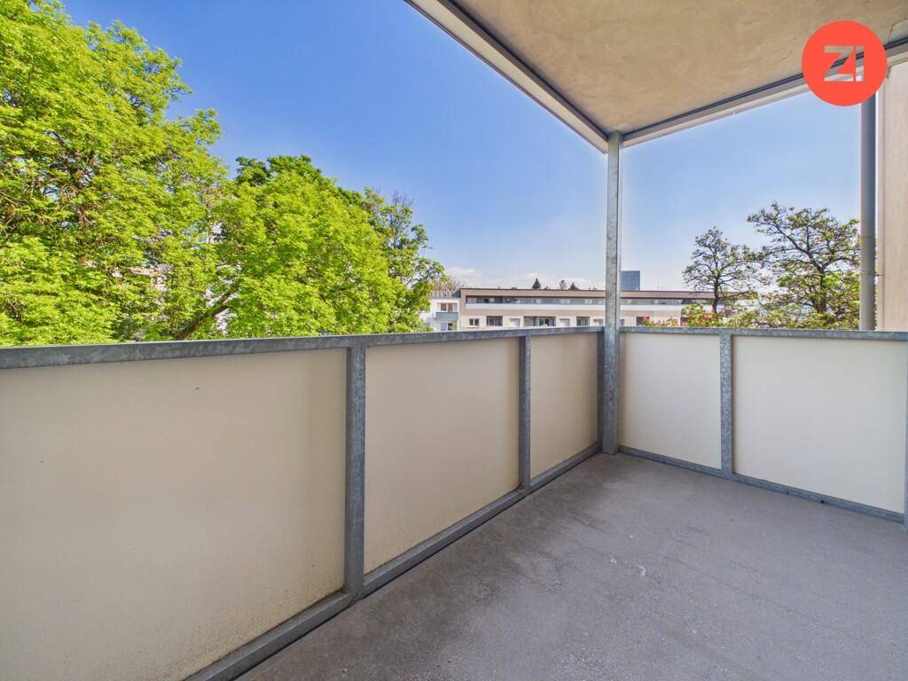 Geräumiger Balkon mit Blick ins Grüne und auf umliegende Gebäude.