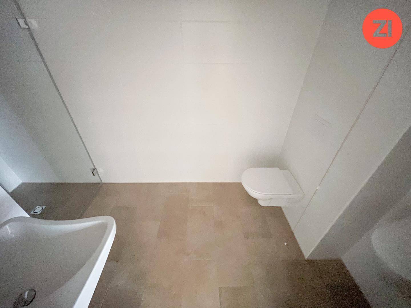 Modernes Badezimmer mit wandhängendem WC, Waschbecken und hellbraunen Fliesen auf dem Boden.