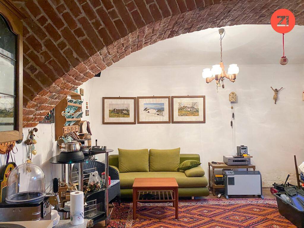 Gemütliches Wohnzimmer mit freiliegendem Ziegelgewölbe, grünem Sofa und traditionellem Teppich.