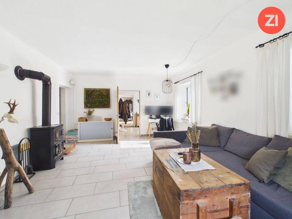 Gemütliches Wohnzimmer mit Kaminofen, Fliesenboden und rustikalem Couchtisch.