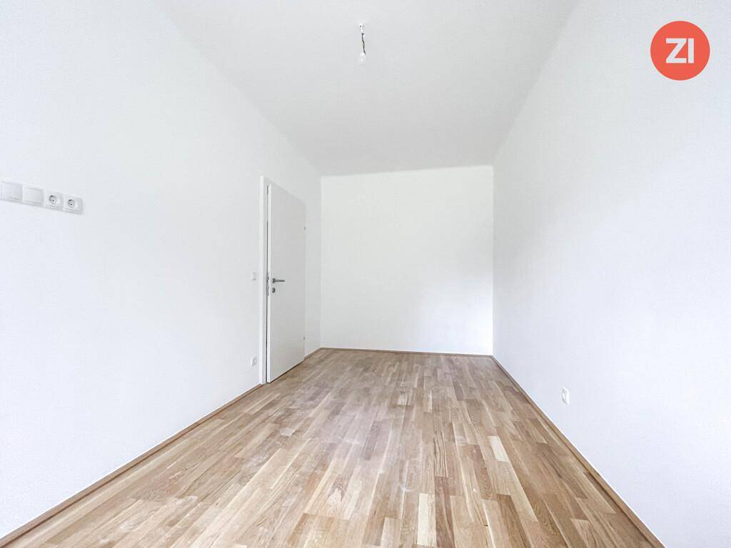 Schlichter, heller Raum mit Holzparkett und weißer Tür, vielseitig nutzbar.