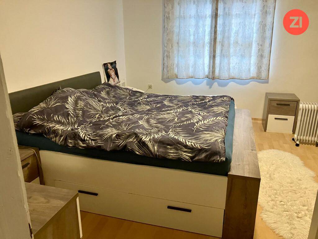 Gemütliches Schlafzimmer mit einem großen Bett, Nachttischen und einem Fenster mit Vorhängen.