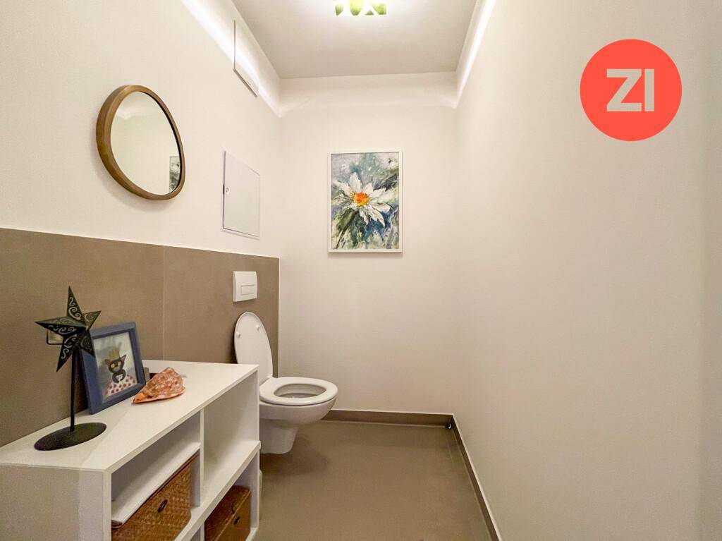 Modernes Gäste-WC mit Wand-WC, Fliesenboden und kleinem Waschbecken.