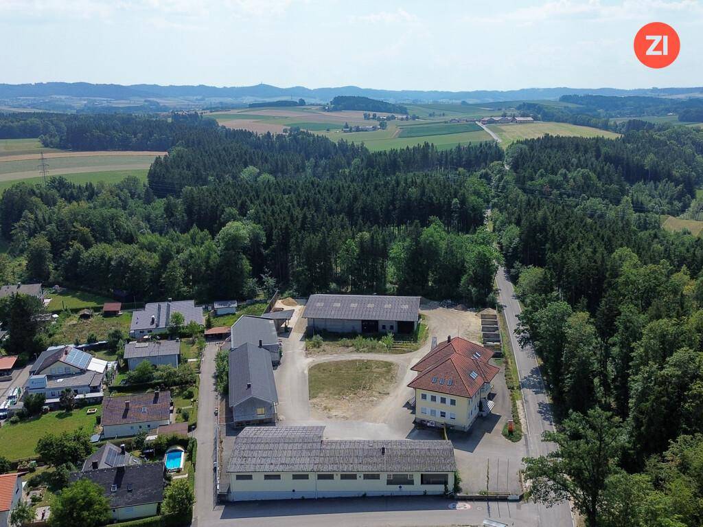 Weitläufige Luftaufnahme des gesamten Anwesens, eingebettet in eine grüne Landschaft mit Wäldern und Feldern.