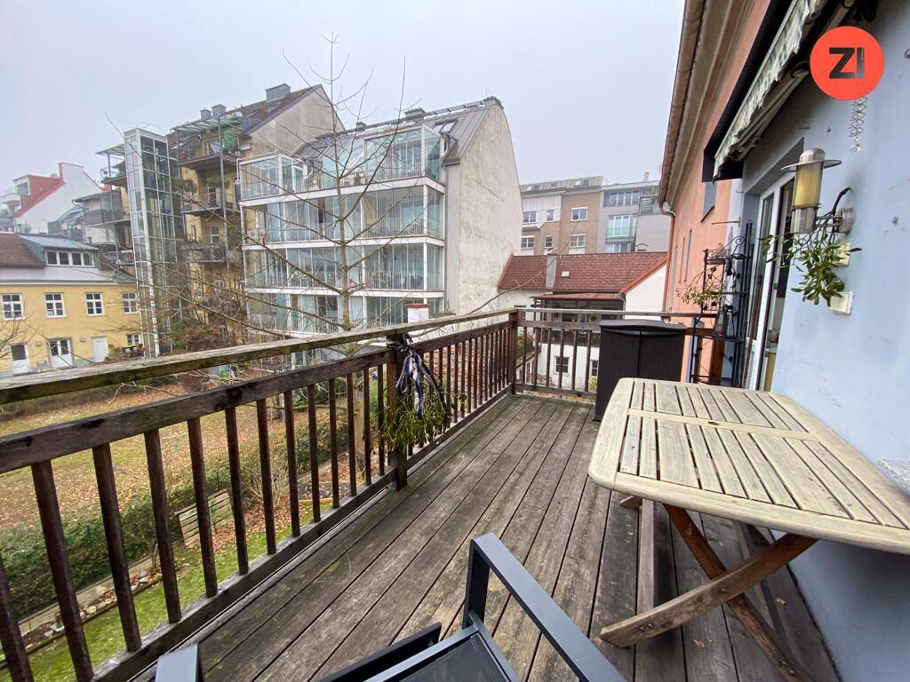 Holzbalkon mit Geländer und einem kleinen Tisch, bietet Blick auf den Garten und die Umgebung.