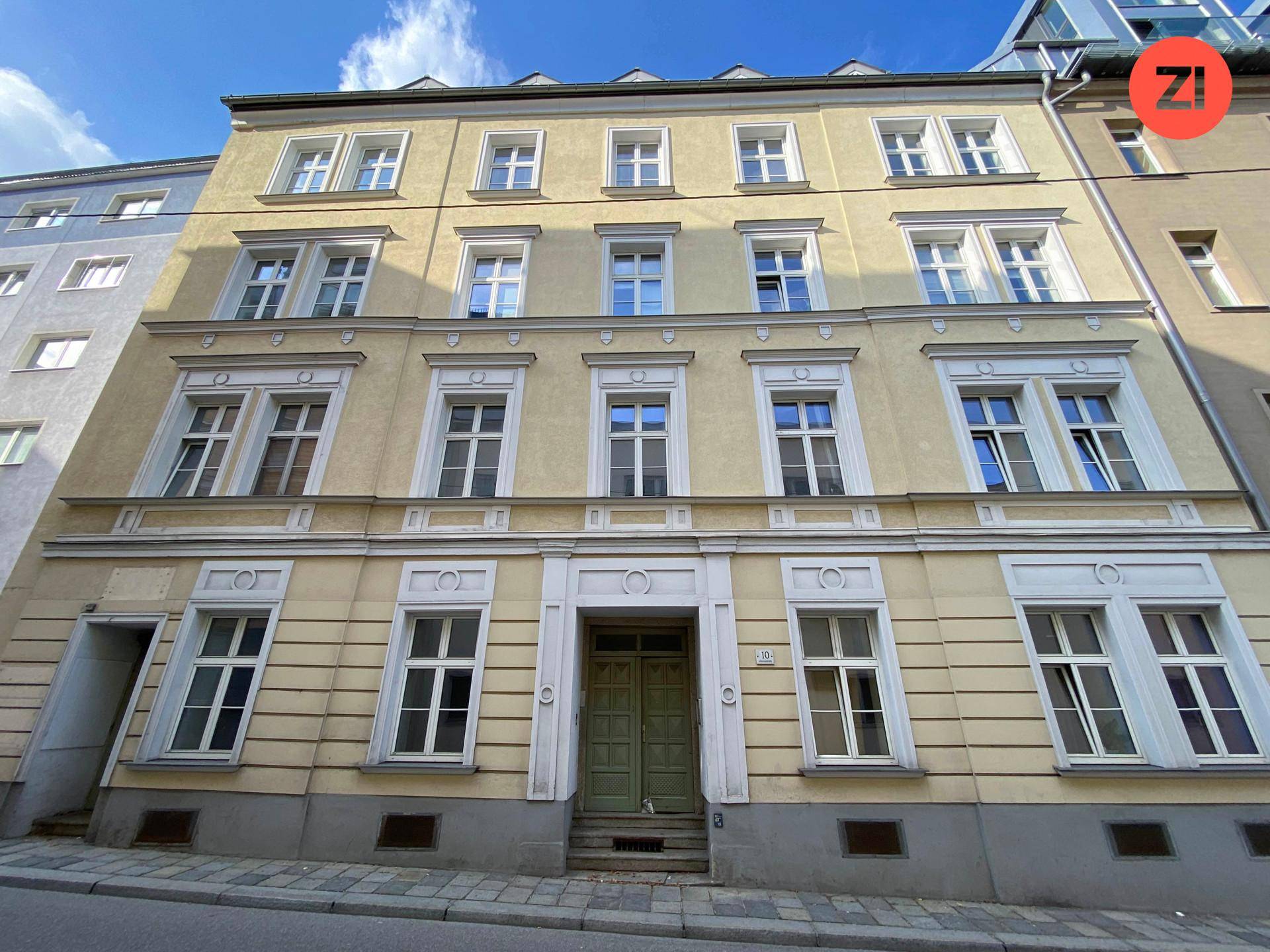 Historische Fassade eines Mehrfamilienhauses mit vielen Fenstern und einem markanten Eingangsbereich.