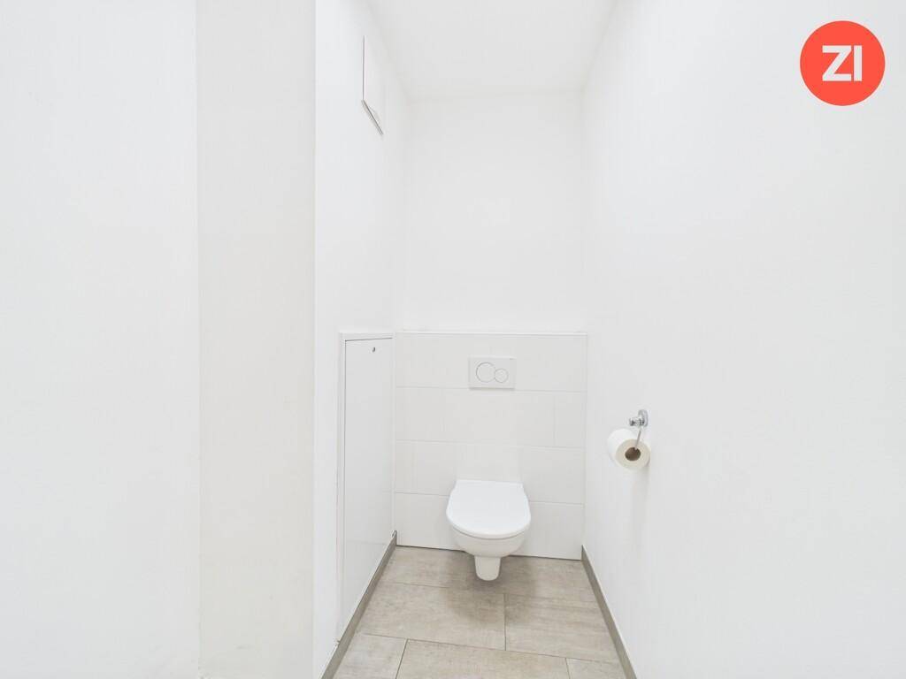 Separates Gäste-WC mit wandhängender Toilette und hellen Fliesen am Boden und an den Wänden.