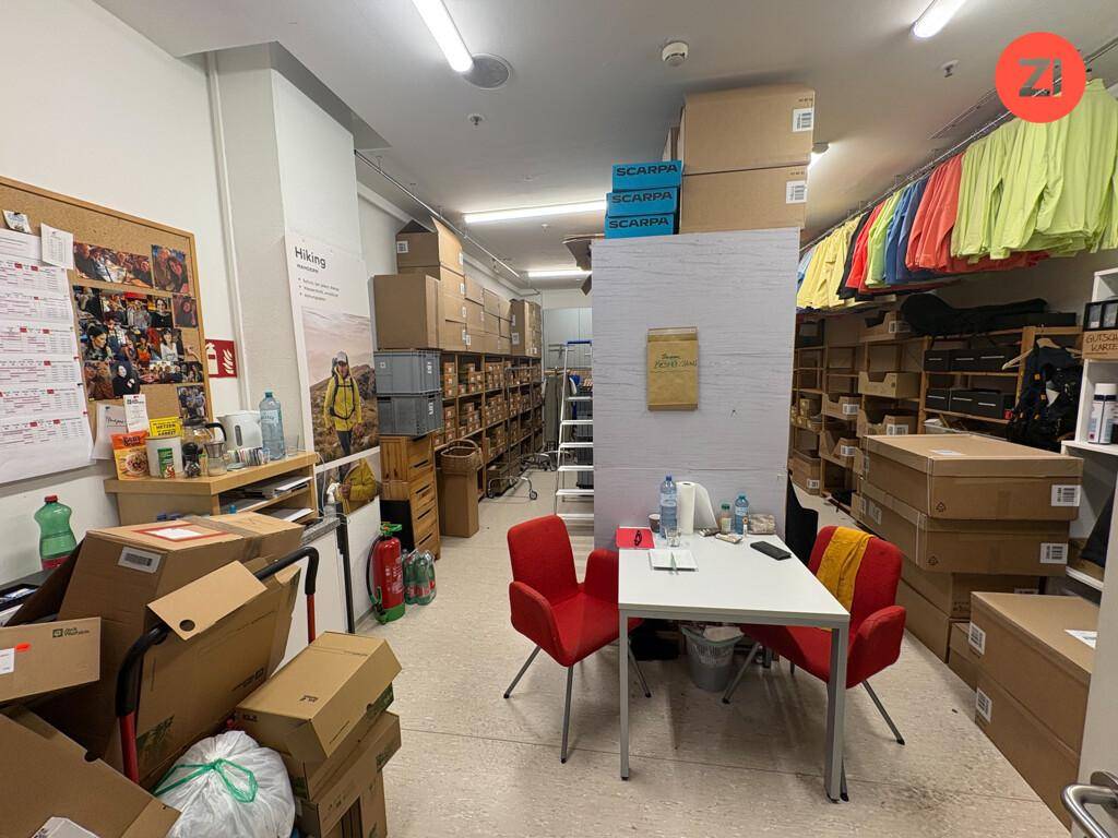 Übersichtlicher Lagerbereich mit vielen Kartons, einem Pinnbrett und einem kleinen Tisch für administrative Aufgaben.