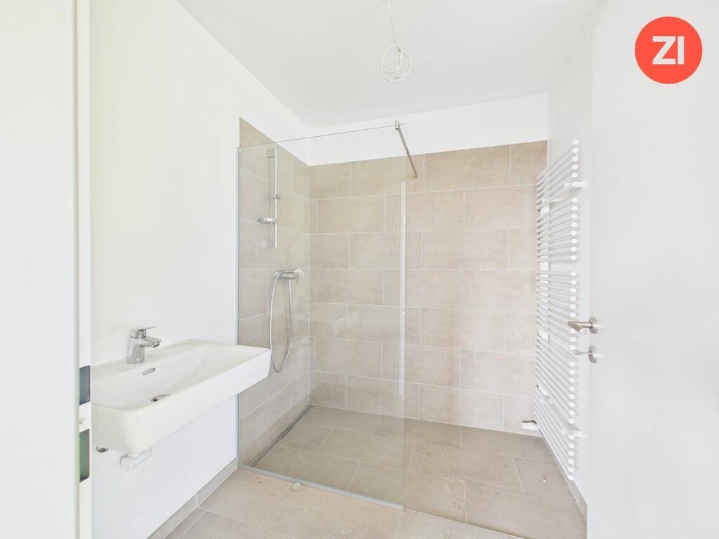 Modernes Badezimmer mit ebenerdiger Dusche, Waschbecken und Handtuchheizkörper.